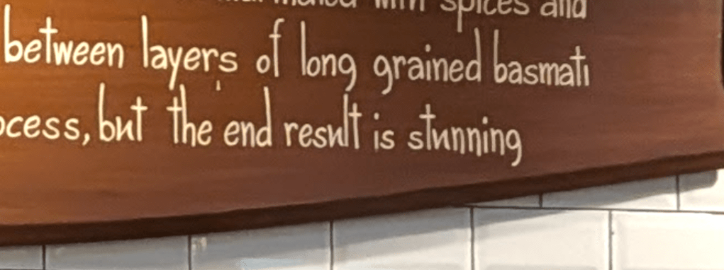 Close-up of biryani restaurant wall text reading the end result is stunning, Delhi